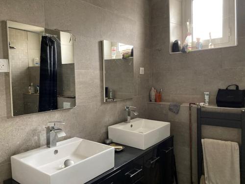 a bathroom with two sinks and two mirrors at Maison chaleureuse, spacieuse à 20 min des pistes in Gap