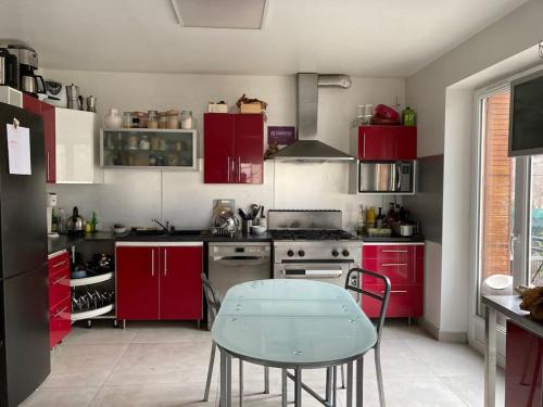 a kitchen with red cabinets and a table in it at Maison chaleureuse, spacieuse à 20 min des pistes in Gap