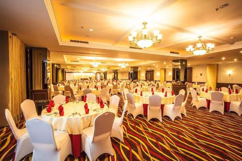a banquet hall with white tables and white chairs at King's Hotel Nagoya Batam in Nagoya