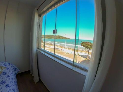 a room with a window with a view of a beach at Apartamento de frente para o mar in Guarapari