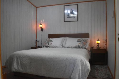 1 dormitorio con 1 cama grande y 2 lámparas en Cabaña El Quijote, en Valdivia