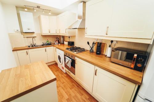 a kitchen with white cabinets and a wooden counter top at Cottages in Derbyshire - Orchard Cottage in Belper