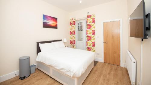 Un dormitorio con una cama blanca y un televisor. en Luxury Shirley Apartments close to Solent Uni and Southampton Central Train Station, en Southampton