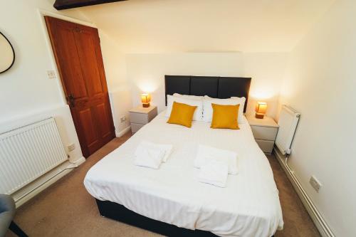 una camera da letto con un grande letto bianco con due cuscini gialli di Cottages in Derbyshire - Orchard Cottage a Belper