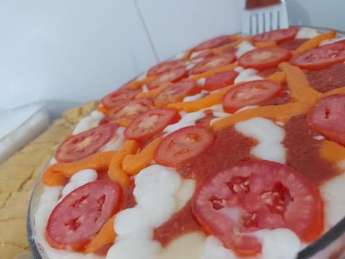 a pizza with tomatoes and sauce on a table at Pousada Mandacaru in Maceió