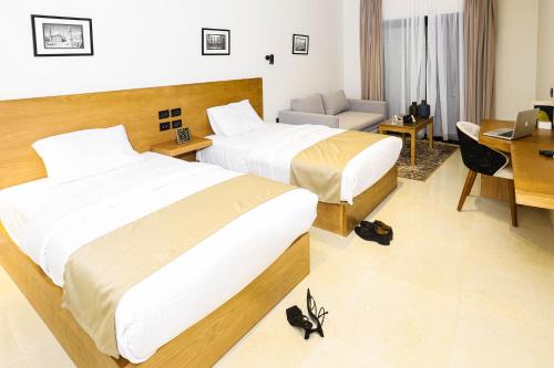 カイロにあるNewCity Hotel & Suitesのベッド2台とデスクが備わるホテルルームです。