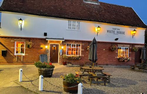 a building with an umbrella and a picnic table at Sibton White Horse Inn in Saxmundham