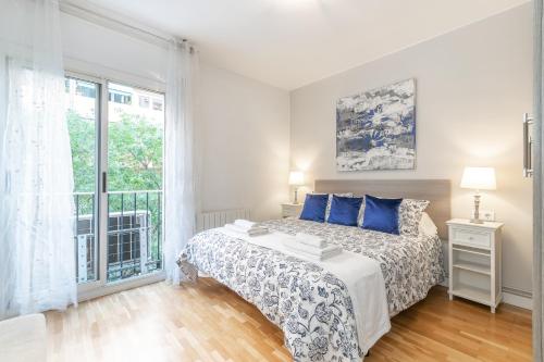 Un dormitorio con una cama con almohadas azules y una ventana en Elegance Barcelona Rentals en Barcelona