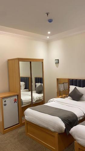 a bedroom with two beds and a mirror at فندق منازل قباء الفندقية in Al Madinah