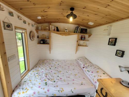 uma cama no canto de uma pequena casa em The Shepherds Hut at Forestview Farm em Greenisland