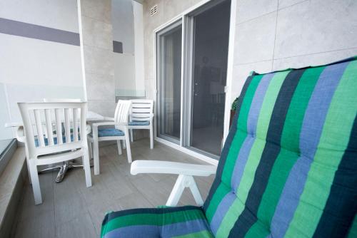 a balcony with a chair and a table and chairs at BEACHFRONT with Seaviews Apartment No56 Award Winner Unbeatable Location for Closeness to the Sea Ideal for Guests looking for Winter Spring and Autumn Breaks in Sunny Malta Also Ideal for Coastal Hikers in Mellieħa