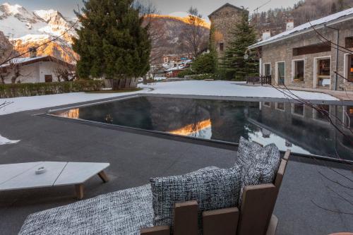 a swimming pool with two chairs and a table at Grand Hotel Royal E Golf in Courmayeur