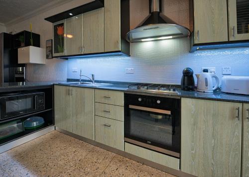 a kitchen with wooden cabinets and a stove top oven at BEACHFRONT with Seaviews Apartment No56 Award Winner Unbeatable Location for Closeness to the Sea Ideal for Guests looking for Winter Spring and Autumn Breaks in Sunny Malta Also Ideal for Coastal Hikers in Mellieħa