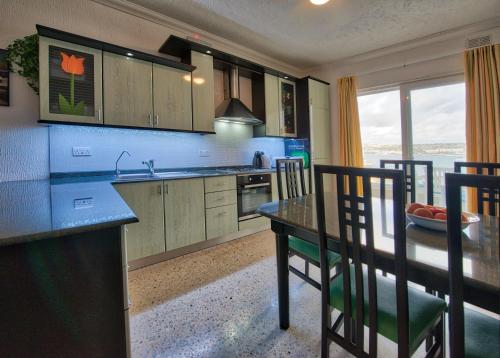 a kitchen with a table and chairs and a dining room at BEACHFRONT with Seaviews Apartment No56 Award Winner Unbeatable Location for Closeness to the Sea Ideal for Guests looking for Winter Spring and Autumn Breaks in Sunny Malta Also Ideal for Coastal Hikers in Mellieħa