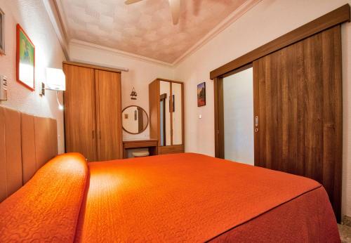 a bedroom with a bed with an orange blanket at BEACHFRONT with Seaviews Apartment No56 Award Winner Unbeatable Location for Closeness to the Sea Ideal for Guests looking for Winter Spring and Autumn Breaks in Sunny Malta Also Ideal for Coastal Hikers in Mellieħa