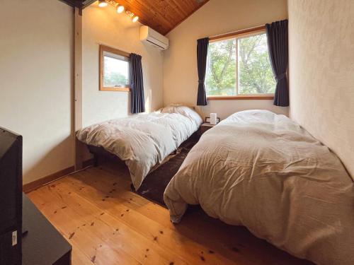 sypialnia z 2 łóżkami i oknem w obiekcie スイートヴィラ 四季terrace箱根仙石原 w mieście Sengokuhara