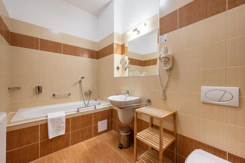 a bathroom with a sink and a tub and a toilet at Hotel Studanka in Rychnov nad Kněžnou