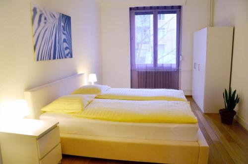 1 dormitorio con 1 cama con sábanas amarillas y ventana en Rent a Home Landskronstrasse - Self Check-In, en Basilea