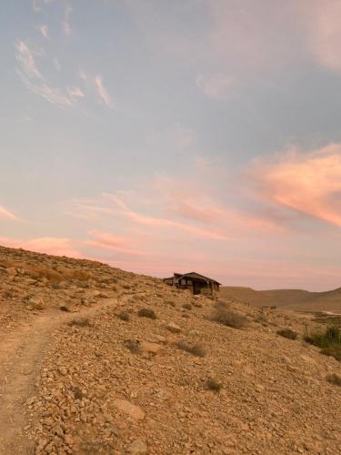 a building in the middle of a desert with a dirt road at Succah in the Desert in Mitzpe Ramon