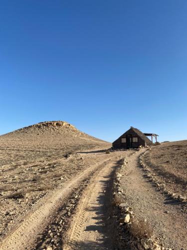 a dirt road leading to a house on a hill at Succah in the Desert in Mitzpe Ramon