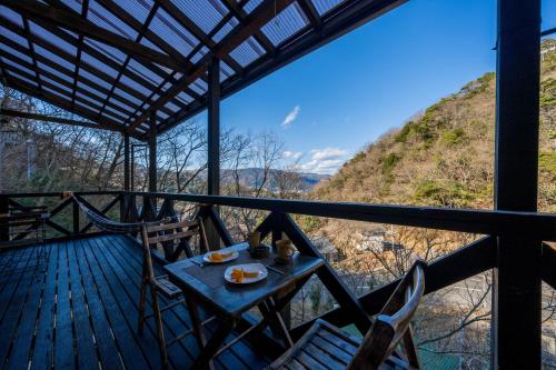 a table and chairs on a deck with a view of a mountain at Suite Villa Minami-Atamigaoka in Atami