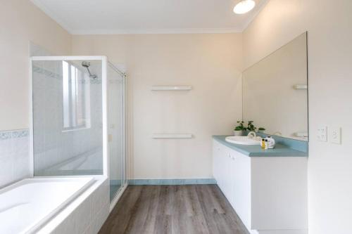 a white bathroom with a tub and a sink at Heart of McKinnon Unit by Ready Set Host in Melbourne