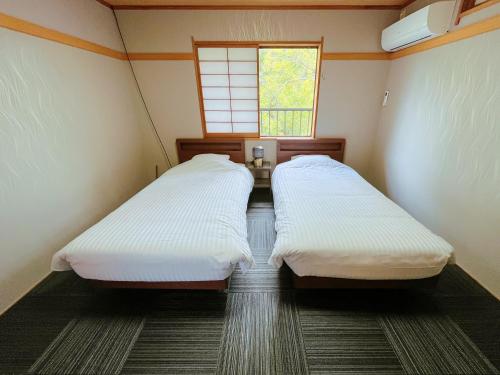 deux lits dans une petite pièce avec une fenêtre dans l'établissement Suite Villa Jogasaki CHABA, à Itō