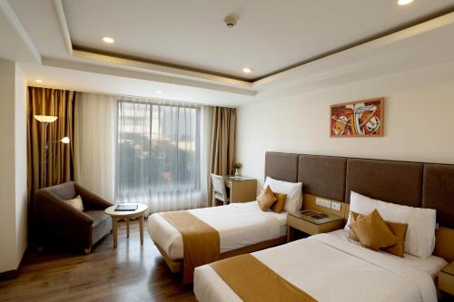 una camera d'albergo con due letti e una sedia di Royale Lalit Hotel Jaipur a Jaipur