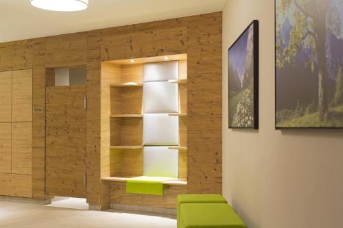 um quarto com uma estante de livros e uma cadeira verde em Liebes Caroline 4-Sterne-Hotel em Pertisau