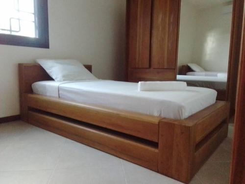 a bed with a wooden bed frame in a room at BEL HORIZON Nosy Be in Nosy Be