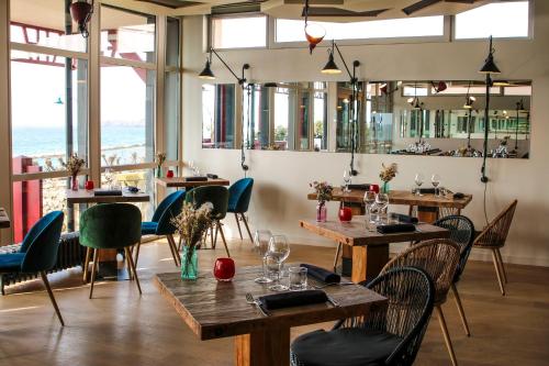 um restaurante com mesas e cadeiras de madeira e janelas em Hôtel Ar Iniz em Saint Malo