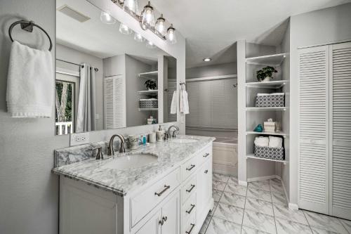 a white bathroom with a sink and a mirror at Crystal River Getaway with Hot Tub and Game Room! in Crystal River