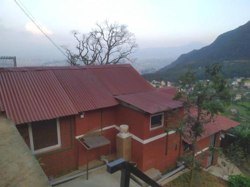 una casa roja con techo rojo en una colina en Penance Homestay, en Khokna