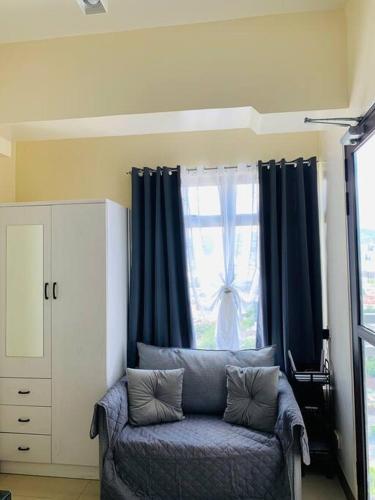 a living room with a blue couch in front of a window at Mabolo Garden Flats 2306 in Cebu City