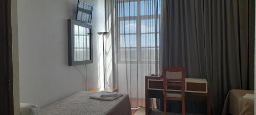 a bedroom with a bed and a chair and a window at Hotel Abade João in Montemor-o-Velho