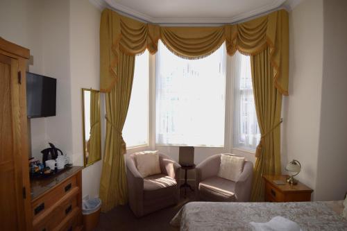 a bedroom with a bed and a window and a chair at Cedar Lodge in Llandudno