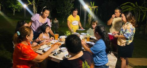 a group of people sitting around a table eating food at Panutsaya Homestay in Wang Nam Khieo