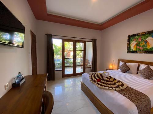 a bedroom with a bed and a desk and a window at Pattri Dihati Lembongan in Nusa Lembongan