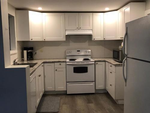 a white kitchen with white appliances and white cabinets at Sleeps 8! Just a 2 minute walk to Beach 1 in Wasaga Beach
