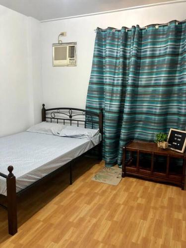 een slaapkamer met een bed en een blauw gordijn bij Sebastians Crib in Dasmariñas