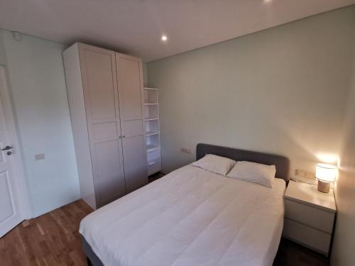 um quarto com uma cama branca e um armário branco em Vytauto 422 Apartments by JK em Palanga