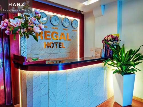 a hotel lobby with a tropical hotel sign and flowers at HANZ Regal Hotel Hanoi in Hanoi