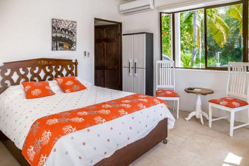 1 dormitorio con 1 cama con almohadas de color naranja y 2 sillas en Villa Mer, en Tivives