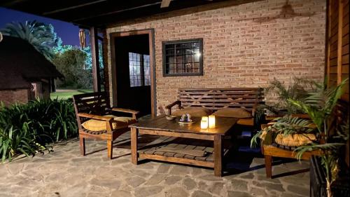 a patio with a table and chairs and a brick wall at Ruda Lodge Exclusive Bed & Breakfast in General Rodríguez