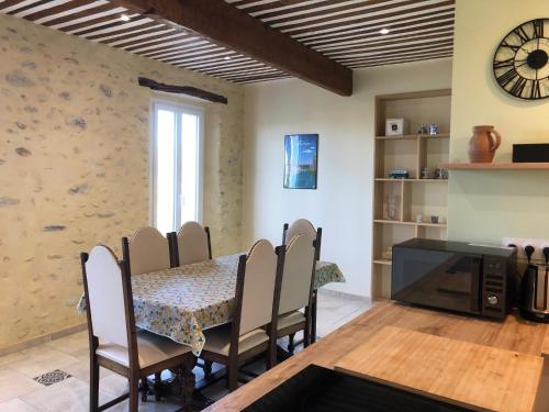 a dining room with a table and chairs and a clock at Maison de charme dans un Hameau Provençal in Les Mées