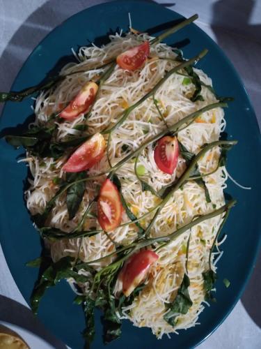 a blue plate of noodles with tomatoes on it at Peacock Residence & Cabana's in Tangalle