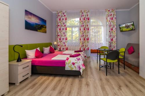 a bedroom with a pink bed and a table at Willa Diament in Kudowa-Zdrój