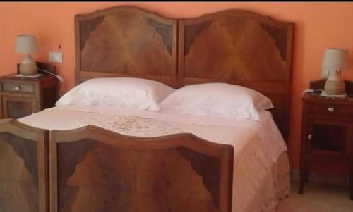 a bedroom with a large wooden bed with white pillows at La lucerna delle dodici stelle in Piglio