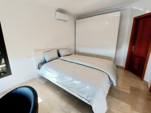uma cama branca num quarto com uma cadeira preta em Villa Playa Amadores - Luxury villa with heated pool em Puerto Rico de Gran Canaria