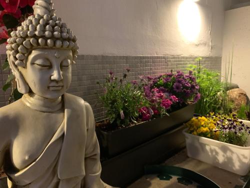 a statue of a buddha next to some flowers at Calatabarca B&B in Tabarca